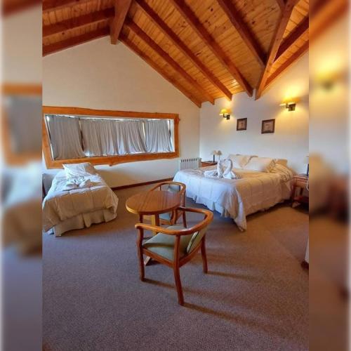 a bedroom with two beds and a table and a chair at Hotel del cerro in Caviahue