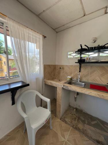 a small kitchen with a sink and a white chair at Apartamentos Coveñas TII in Coveñas