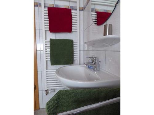 a bathroom with a white sink and red and green towels at Holiday home with 2 bedrooms in Greetsiel