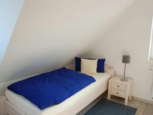 a bedroom with a bed with blue sheets and a lamp at Holiday home with 2 bedrooms in Greetsiel