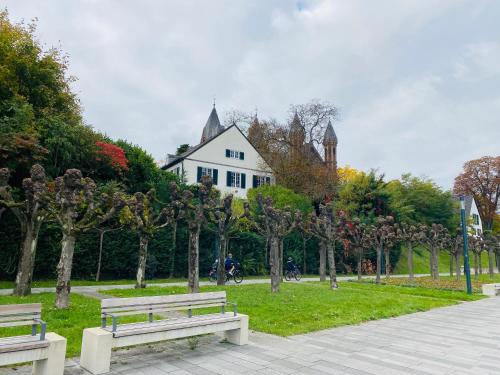 two benches in a park with a house in the background at Nido Vela Appartement in Wesseling