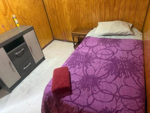 a bedroom with a purple bed and a chair at Casa España in Punta Arenas