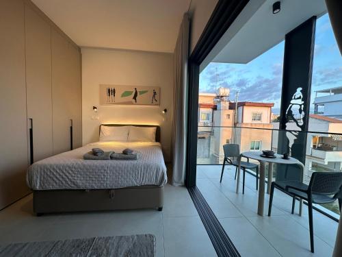 a bedroom with a bed and a balcony with a table at Nesseus Lux Suites - Near Unic & EUC in Ayios Dhometios