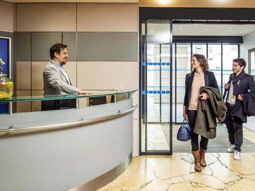 a man and a woman standing in a lobby at Aparthotel Adagio La Défense Kléber in Courbevoie
