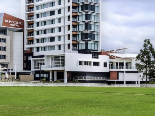 a building with a grass field in front of it at Mercure Sydney Liverpool in Liverpool
