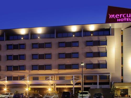 a hotel with cars parked outside of it at night at Mercure Sydney Liverpool in Liverpool