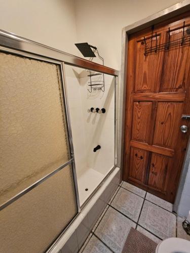a shower with a glass door in a bathroom at The Carnival Residence at Queens Park Savannah in Valencia Village