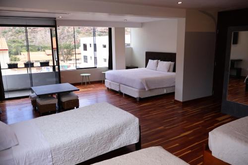 Una habitación de hotel con dos camas y una gran ventana. en Hotel California Urubamba, en Urubamba
