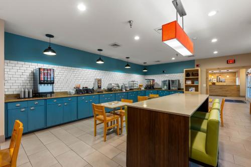 a large kitchen with blue cabinets and yellow chairs at Country Inn & Suites by Radisson, Asheville - Outlet Mall in Asheville