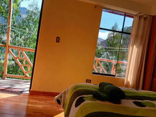 a bedroom with a bed and a large window at Hilo Verde in Pisac