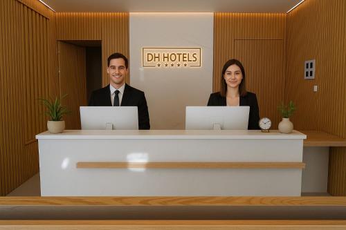 two people sitting at a reception desk with laptops at Hotel Infante Santo - Lisboa in Lisbon