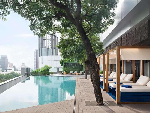 a pool on the rooftop of a building with a tree at Novotel Bangkok Platinum Pratunam in Bangkok