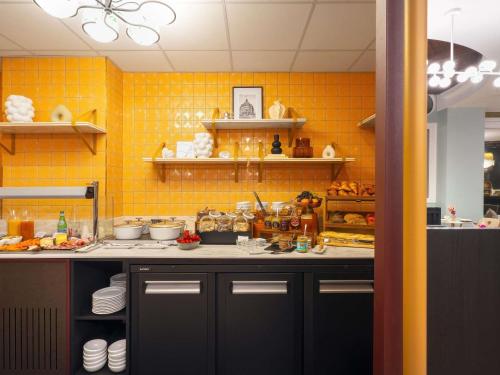 a kitchen with yellow tiles on the wall at Grand Hotel des Brotteaux Lyon Ctre - Handwritten Collection in Lyon