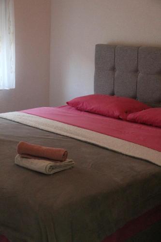 a bed with red sheets and two towels on it at Kuća za odmor Ana in Oklaji