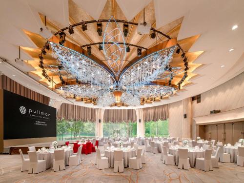 einen Bankettsaal mit weißen Tischen und einem großen Kronleuchter in der Unterkunft Pullman Shanghai Central - In XinTianDi & Yu Garden Area in Shanghai