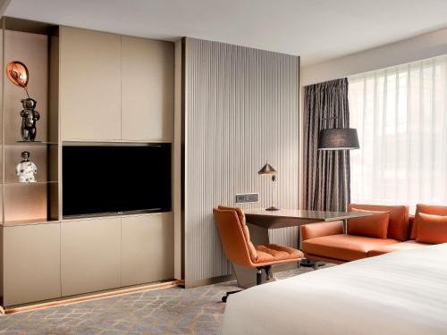 ein Hotelzimmer mit einem Bett, einem Schreibtisch und einem Fernseher in der Unterkunft Pullman Shanghai Central - In XinTianDi & Yu Garden Area in Shanghai
