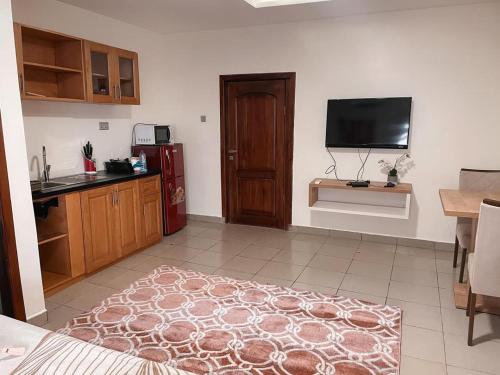 um quarto com uma cozinha com uma televisão e uma porta em Bosco em Accra