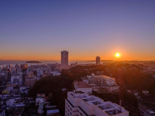 a city skyline with the sun setting in the sky at Mercure Yokosuka in Yokosuka