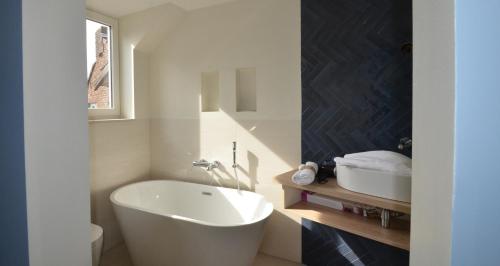 Un baño con bañera blanca y lavabo. en Leukderhuisje Geulle, en Guelle