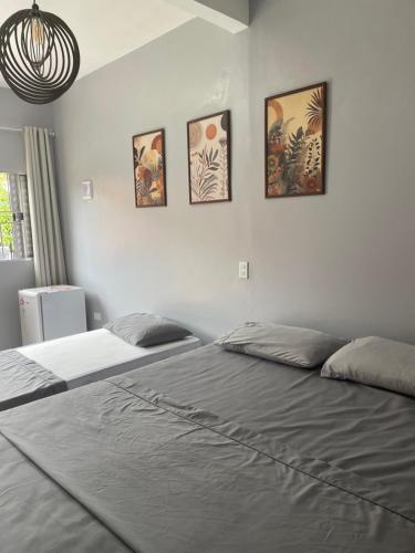 a bedroom with two beds and four pictures on the wall at Pousada Rural Ouro Verde in Eldorado