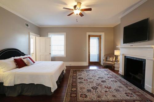 a bedroom with a bed with a ceiling fan and a fireplace at Oglethorpe Manor Main House in Savannah