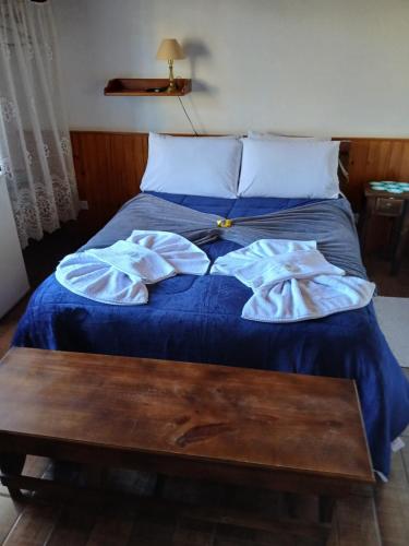 a bed with blue sheets and a table on it at Pousada dos Pássaros in Camanducaia