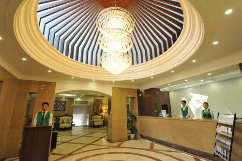 a lobby with a large ceiling and two people standing at a counter at Flower Hotel Ulaanbaatar in Ulaanbaatar