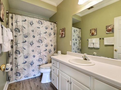 Un baño con lavabo, inodoro y cortina de ducha. en South Beach Retreat, en Tybee Island