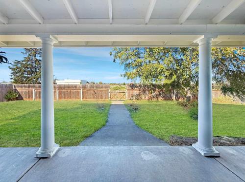 a porch with white columns and a grass field at Alderwood Escape in Sequim