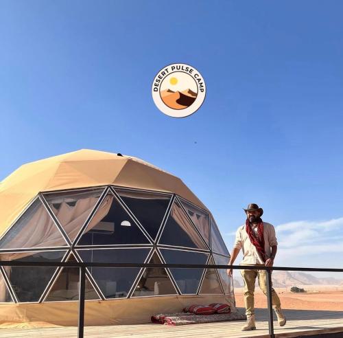 a man standing next to a tent in the desert at RUM BULSE BUBBLE lUXURY CAMP in Disah