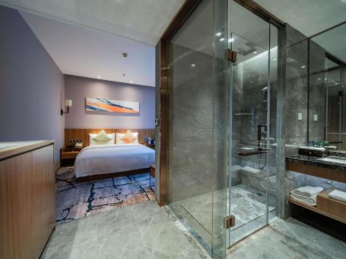 a bathroom with a shower and a bedroom with a bed at Novotel Guiyang Downtown in Guiyang