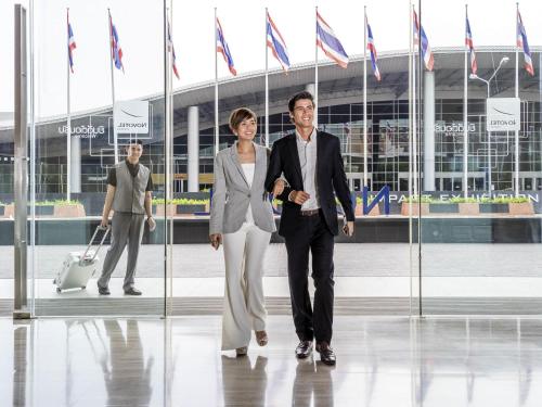 a man and a woman walking in front of a building at Novotel Bangkok IMPACT in Nonthaburi
