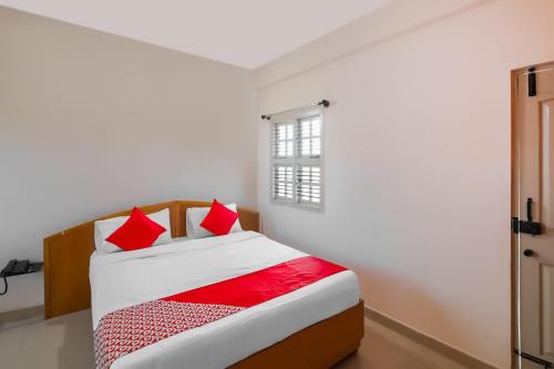 a bedroom with a bed with red pillows at Hotel O Narayani Residency in Mysore
