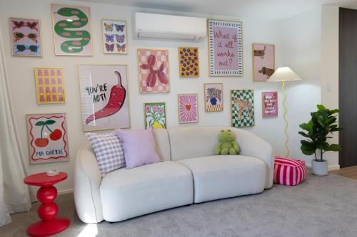 a living room with a white couch and a wall of pictures at Colour Burst Townhouse in Christchurch