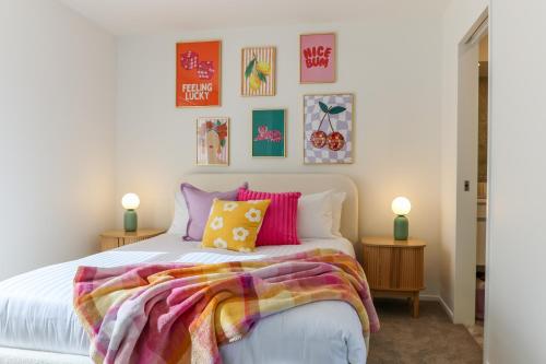 クライストチャーチにあるColour Burst Townhouseの白いベッドとカラフルな枕のある寝室