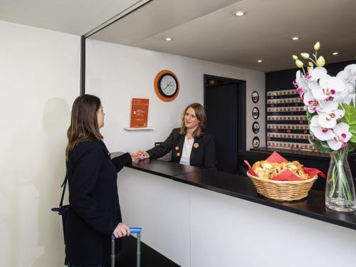 two women shaking hands at a counter in a hair salon at Aparthotel Adagio Access La Défense - Place Charras in Courbevoie