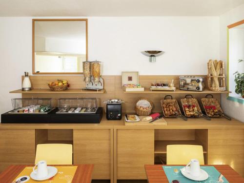 a kitchen with a counter with two tables and a mirror at Aparthotel Adagio Access La Défense - Place Charras in Courbevoie
