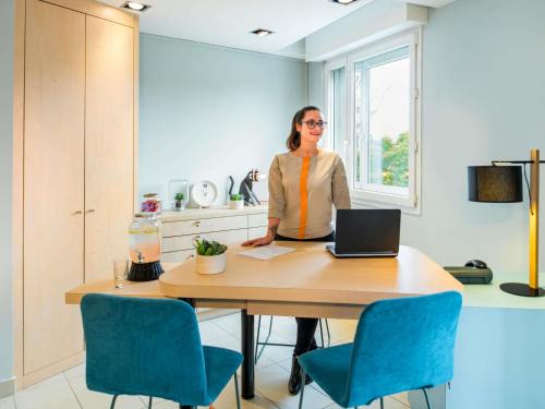 a woman standing at a table with a laptop at Aparthotel Adagio Access Paris Porte De Charenton in Charenton-le-Pont