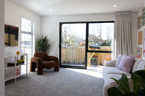 a living room with a white couch and a tv at Colour Burst Townhouse in Christchurch