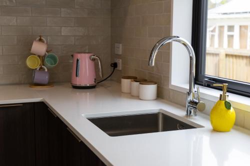 クライストチャーチにあるColour Burst Townhouseのキッチン(シンク、ピンクの電化製品付)