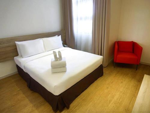 a hotel room with a bed and a red chair at Rooms By Rocana in Kuantan