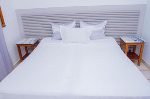 a bed with white sheets and pillows in a room at Casa 13 - Refúgio Salinas in Vila do Maio