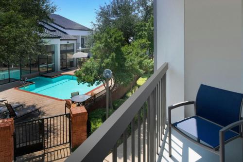 a balcony with a blue chair and a swimming pool at Courtyard Dallas Las Colinas in Irving