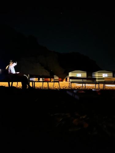 Fire bedouin camp في وادي رم: امرأة تجلس على مقعد ليلاً