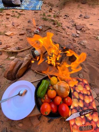 a fire with a bowl of fruit and a plate of vegetables at Fire bedouin camp in Wadi Rum