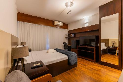 a bedroom with a bed and a tv and a couch at Flats Hotel Paulista | Delfhy in São Paulo