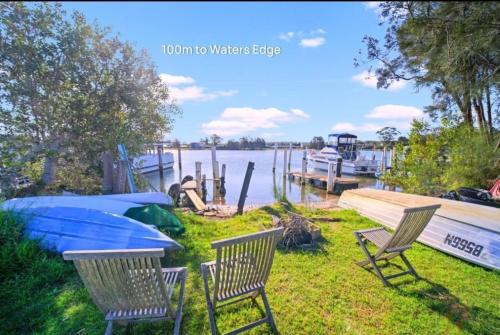 a couple of chairs and a table and a boat at Tuncurry 2BR Walk to Lake in Tuncurry