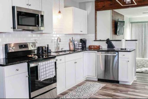 a kitchen with white cabinets and stainless steel appliances at Midtermlongterm Buckroe Beach Bungalow Ev Chrg in Hampton