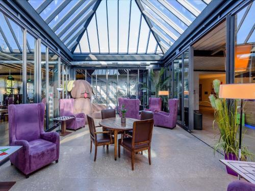 a dining room with purple chairs and a table at ibis Styles Leipzig in Radefeld