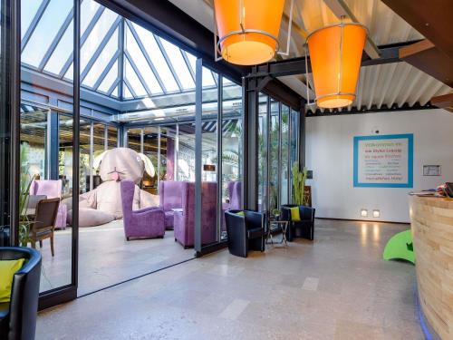 Radefeldにあるイビス スタイル ライプツィヒの紫色の椅子とスライドが備わる広い客室です。